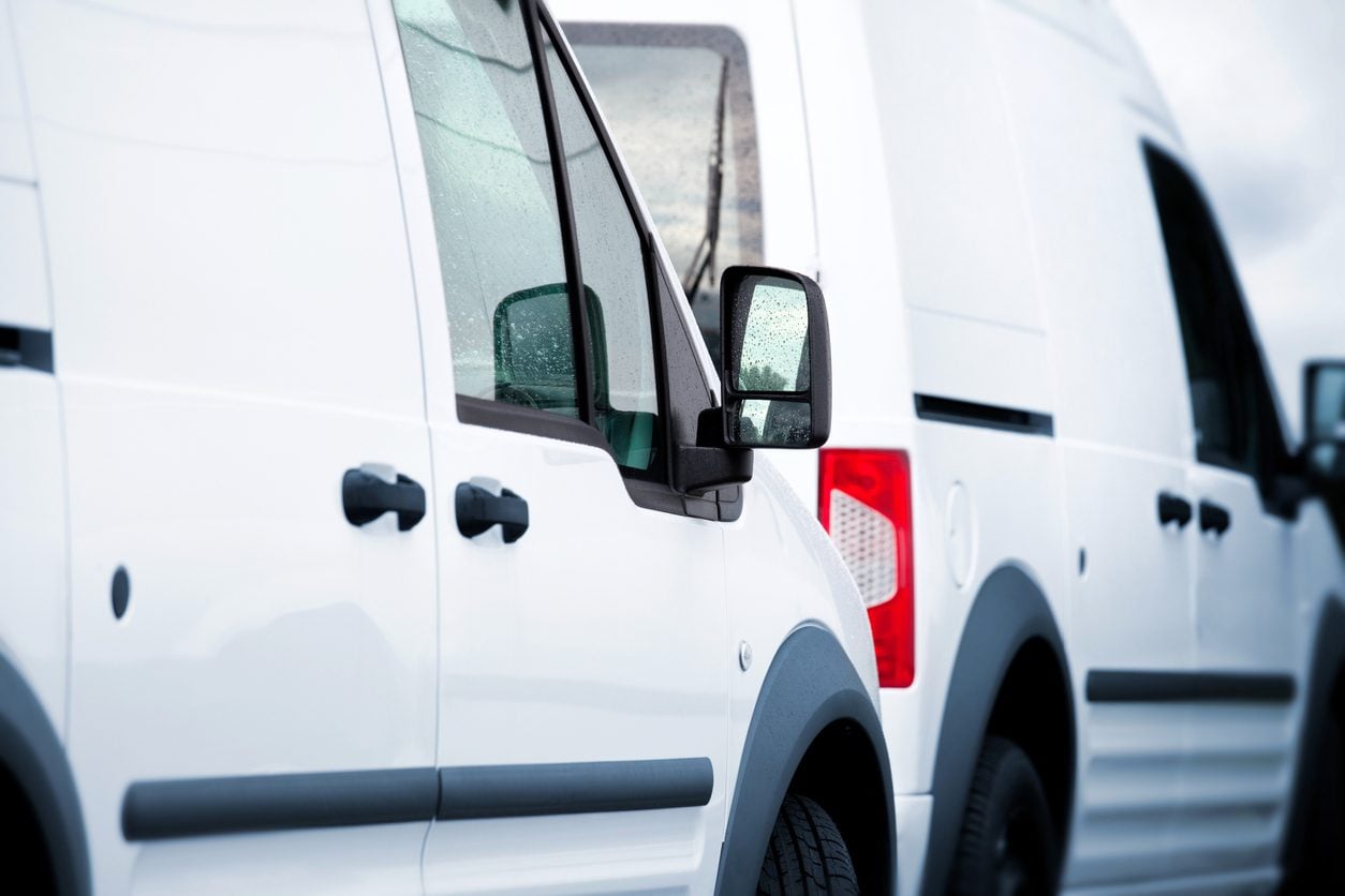 Two white cargo vans parked side by side