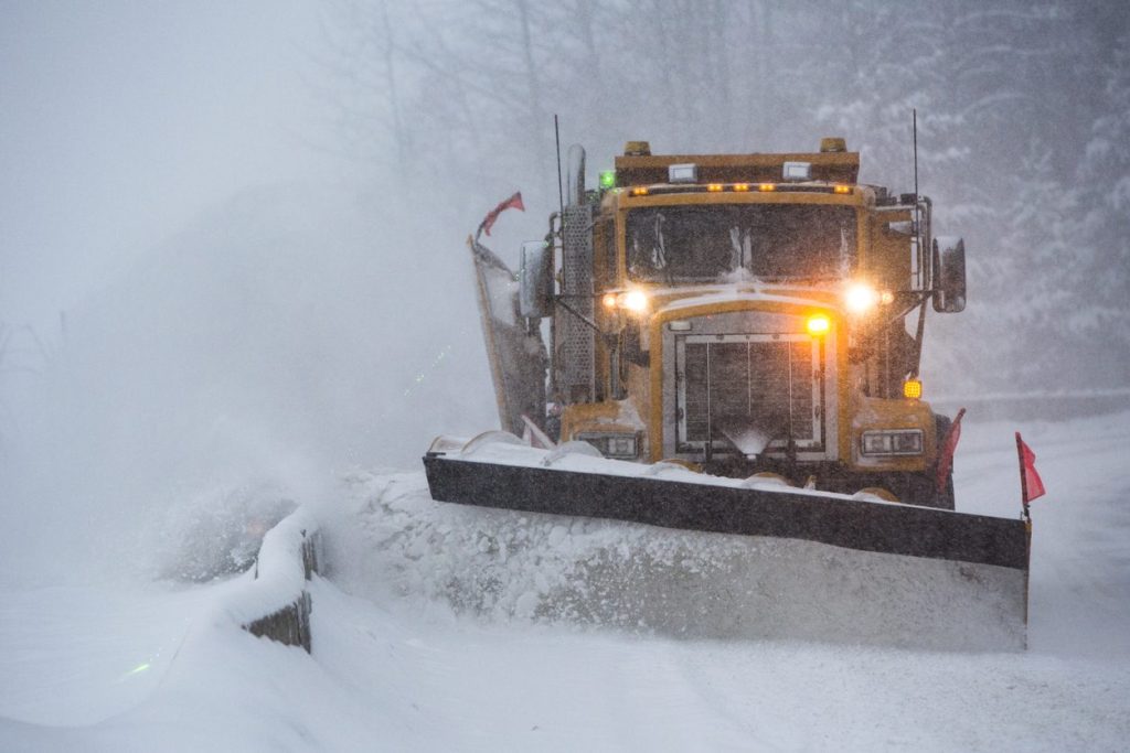 Municipal plow truck clearing a highway in a snowstorm