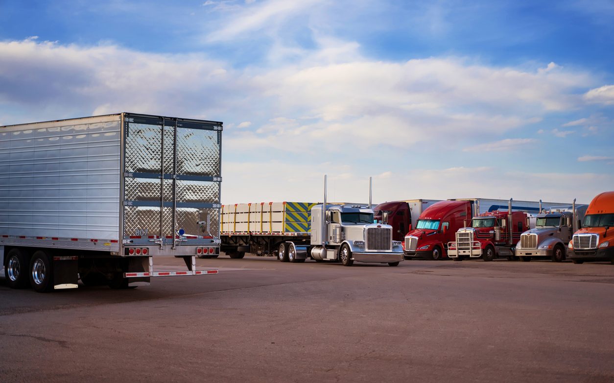 Conventional tractors and trailers parked at a truck stop at dusk