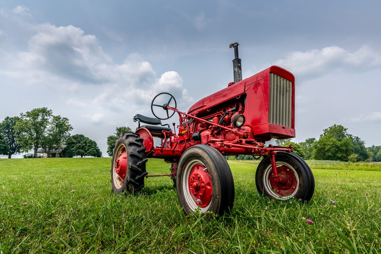 Vintage red tractor standing in a green field