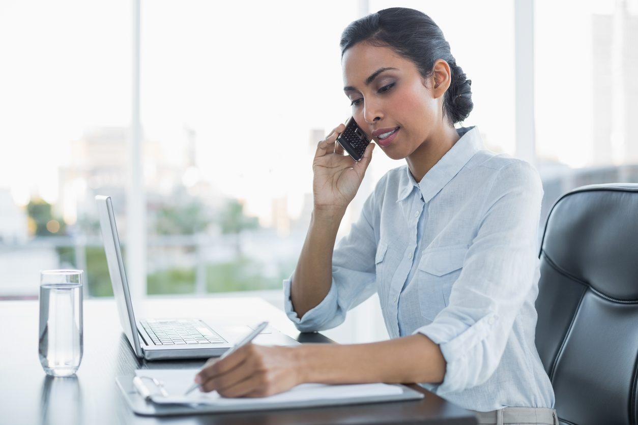 Woman checking records at a desk with a laptop