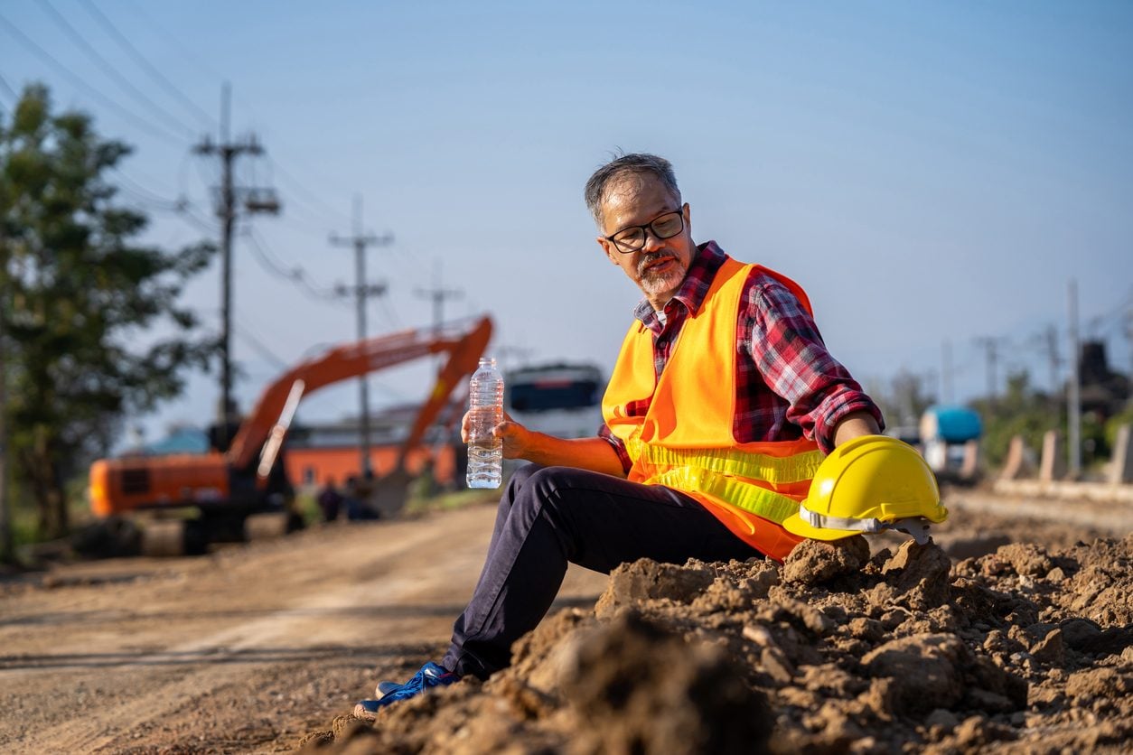 Worker in a high visibility vest drinking water during a break in midday heat