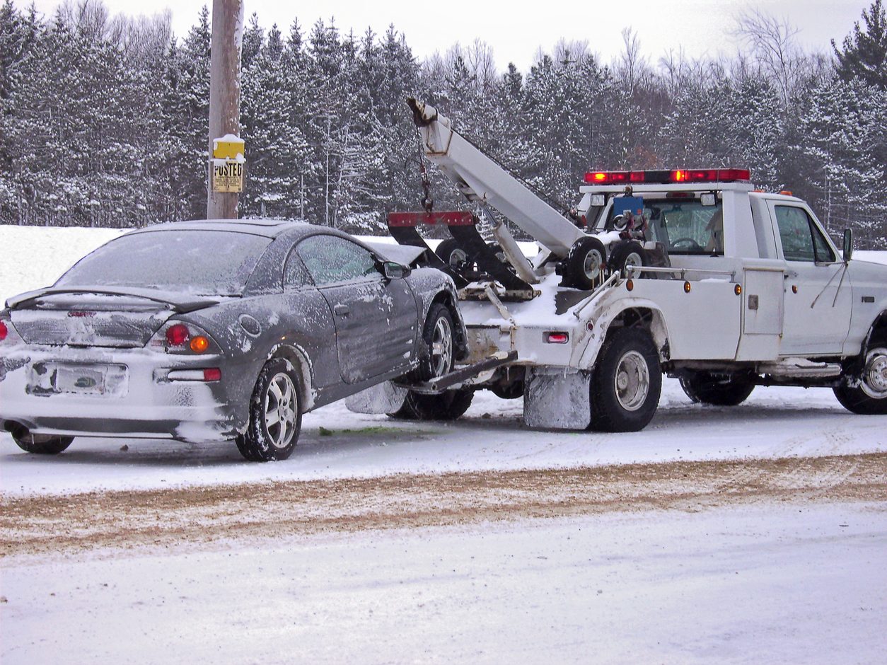 Wrecker lifting a damaged car at the roadside in snow
