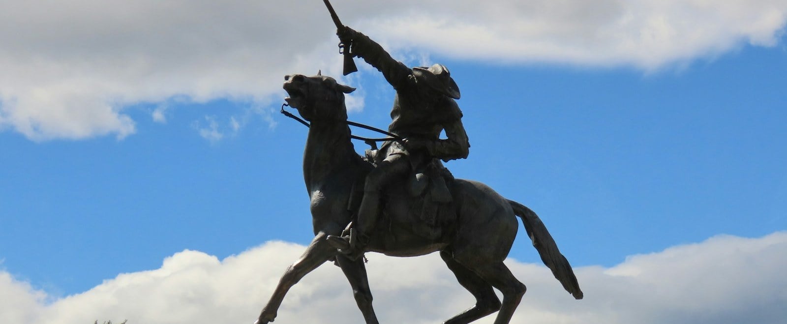 Bronze statue of Buffalo Bill on horseback with rifle raised in Cody