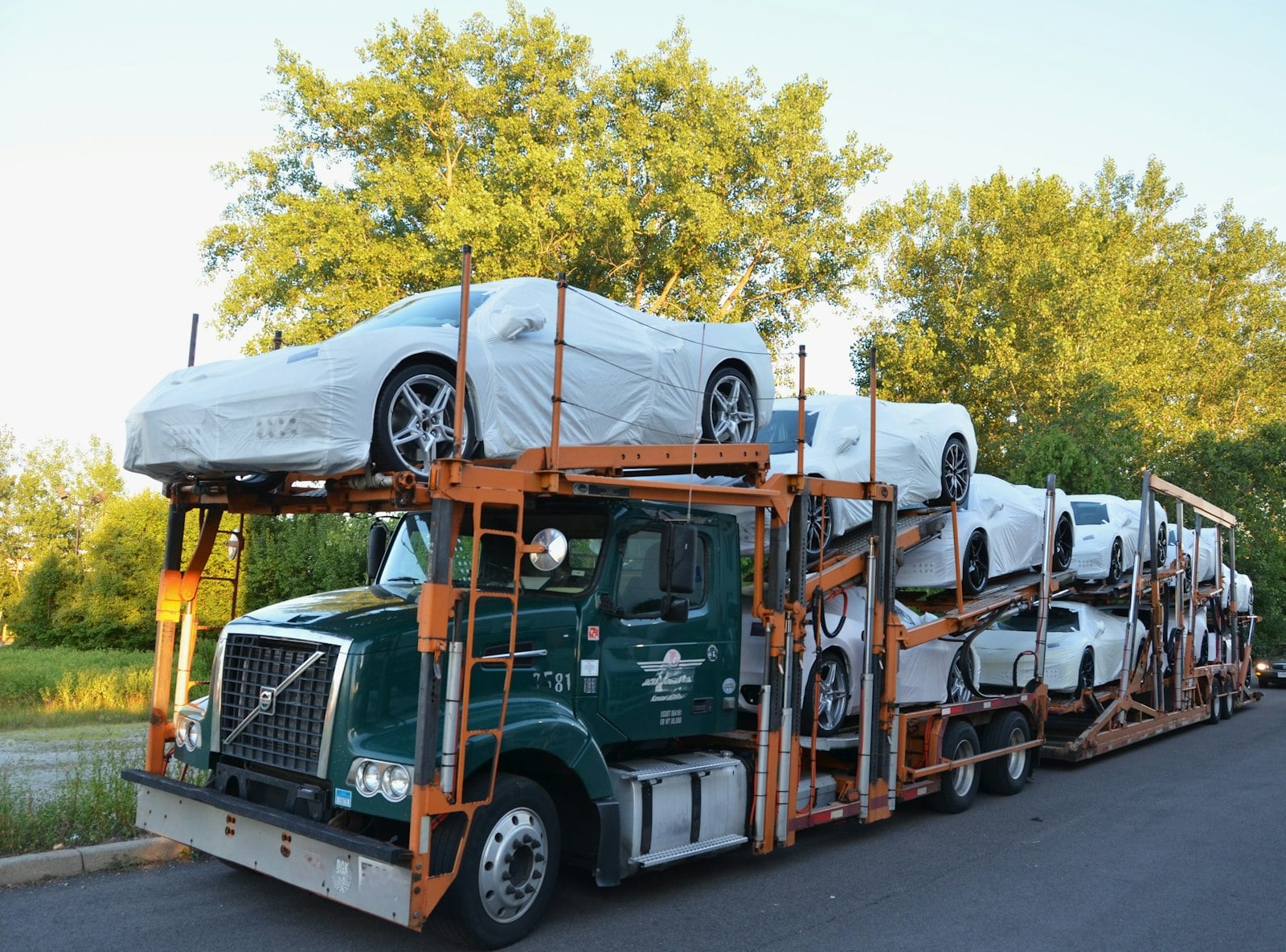 New Corvettes in white protective wrap stacked on an open car carrier