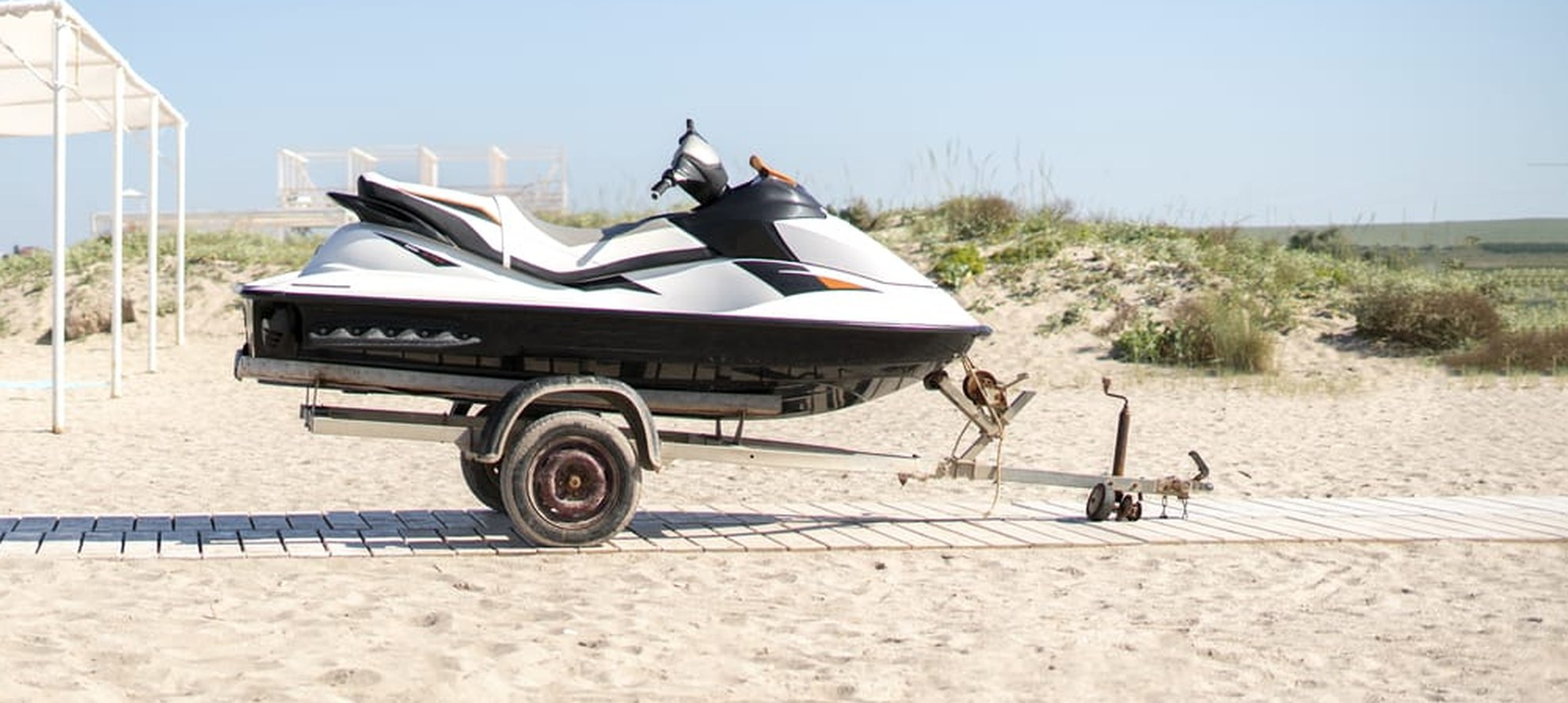 Personal watercraft strapped to a single-axle road trailer with the tow hitch visible