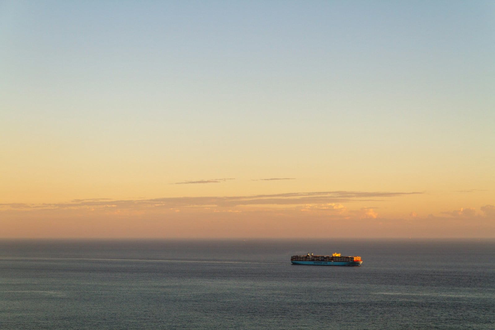 Container ship crossing open ocean at sunset