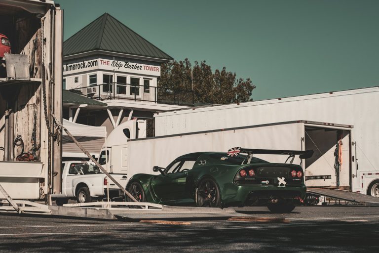 Race car staged beside enclosed car hauler trailers with the ramps down
