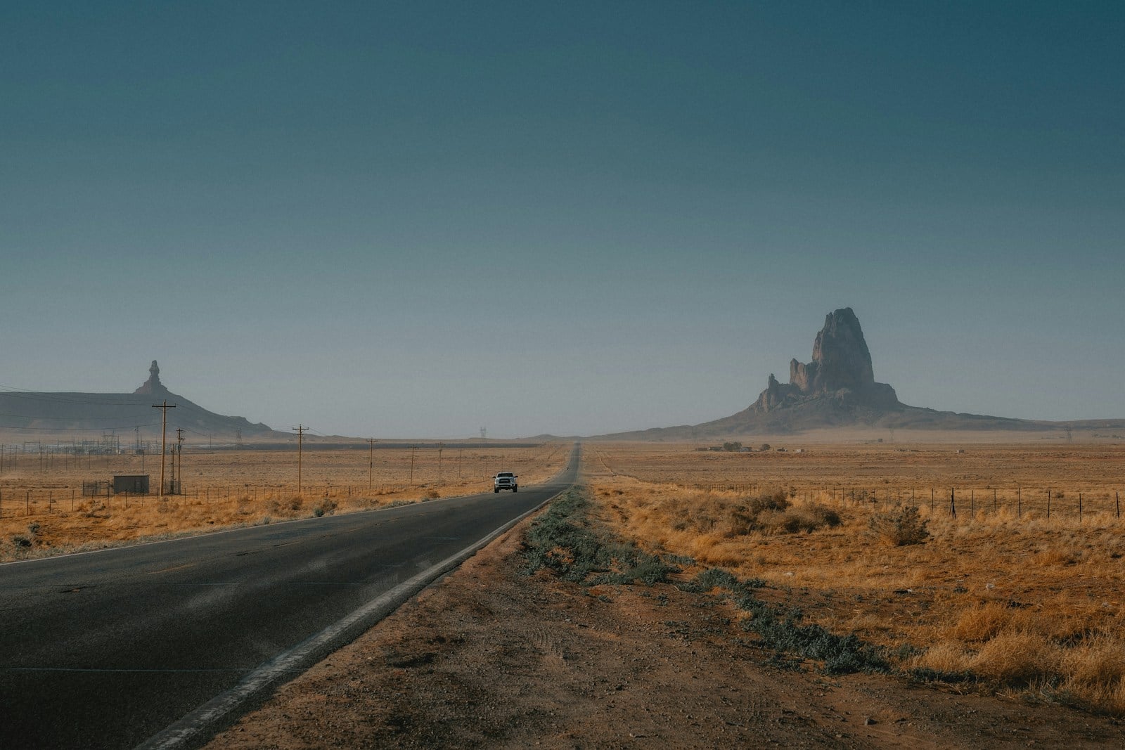 Lone pickup on an open Arizona highway with a desert butte on the horizon