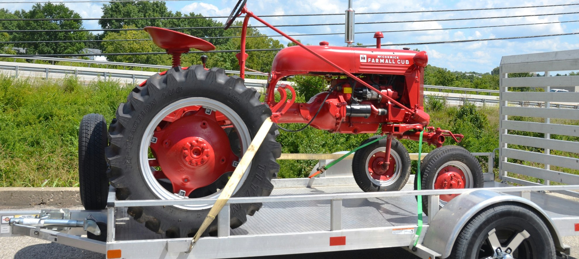 Restored farm tractor strapped to an aluminum utility trailer for transport